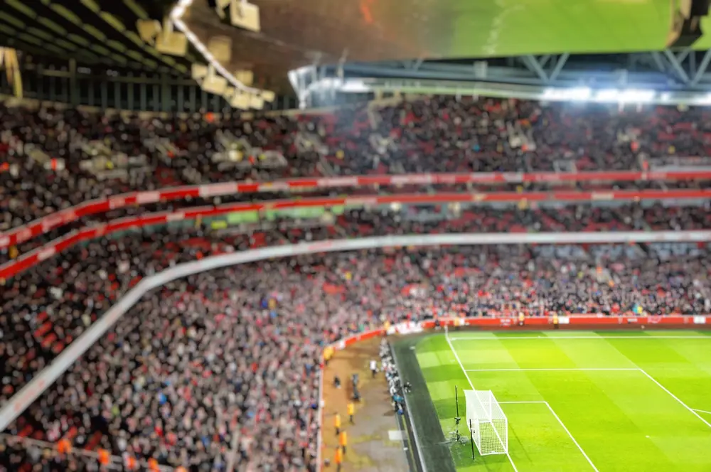 Blurred,Background,Of,Football,Players,Playing,And,Soccer,Fans,In Blurred,Background,Of,Football,Players,Playing,And,Soccer,Fans,In